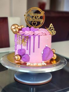 a pink and gold birthday cake sitting on top of a table