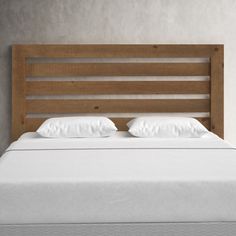 a bed with white pillows and wooden headboard