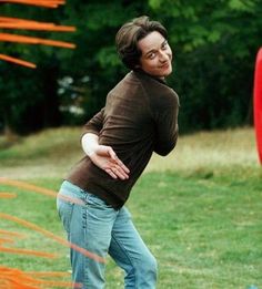 a man is throwing a red frisbee on the grass with trees in the background