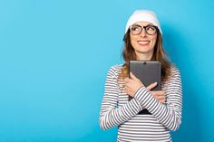 a woman wearing glasses and a white hat holding a tablet