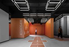 a person walking down a long hallway with orange walls and flooring on both sides