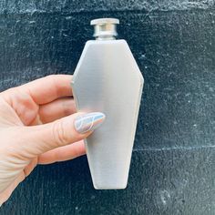 a woman's hand holding onto a bottle shaped like a hexagonal object