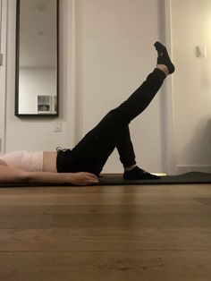 a woman laying on the floor with her legs up in the air while doing an exercise