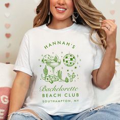 a woman sitting on a couch wearing a t - shirt that says hannah's bachelor beach club