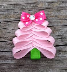 a pink hair bow with white polka dots on it and a green clip in the shape of a christmas tree