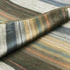 a multicolored rug is laying on top of a tablecloth with a rolled up piece of fabric next to it