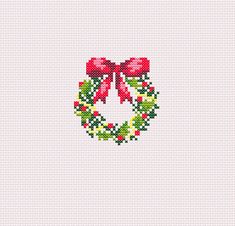 a cross stitch christmas ornament with a red bow and green wreath on it