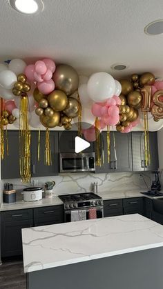 balloons and streamers are hanging from the ceiling above a kitchen island in an apartment