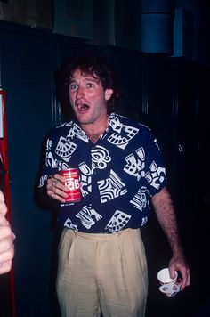 a man holding a drink in his hand and making a surprised face while standing next to a vending machine