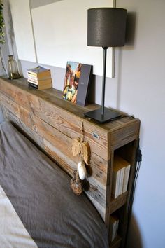 a bed with a wooden head board on top of it next to a lamp and pictures