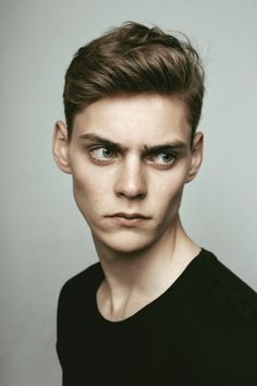 a close up of a person wearing a black shirt and looking at the camera with a serious look on his face