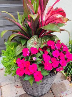 a basket filled with lots of flowers sitting on top of a brick floor next to a building