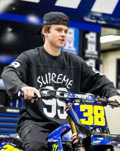 a young man riding on the back of a blue dirt bike