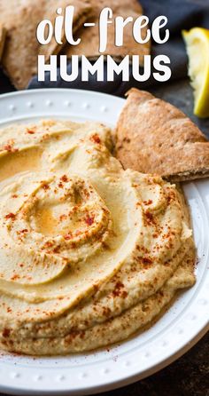 hummus on a plate with pita bread and lemon wedges in the background