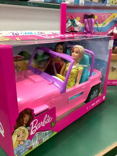 two barbie dolls in a pink toy car