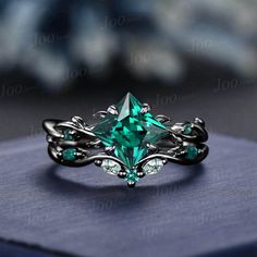 a ring with an emerald green stone in the center on top of a blue box