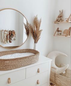 a baby crib in front of a round mirror and shelf with baskets on it