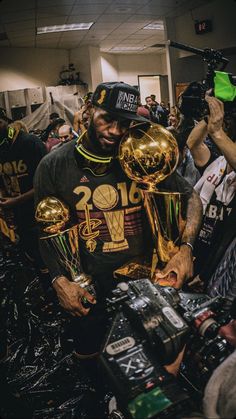 the basketball player is holding trophies and posing for pictures with his fans in front of him