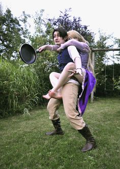 a man and woman are in the grass playing with a frisbee while holding each other