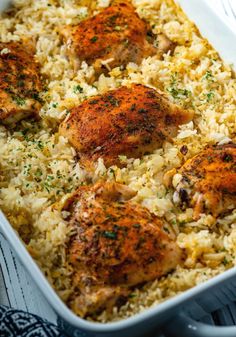 chicken and rice in a white casserole dish with parsley on top, ready to be eaten