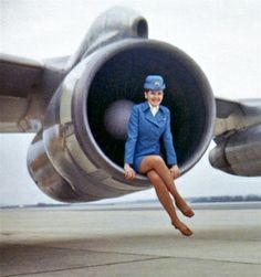 a woman in an air force uniform is sitting on the nose of a jet airplane