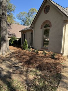 a house that is in the middle of some grass and dirt with trees around it