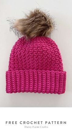 a pink knitted hat with a fur pom