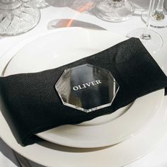 a white plate topped with a black napkin next to a wine glass and silverware