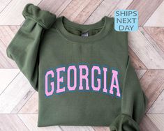 Georgia Sweatshirt, Georgia T shirt, College Sweatshirt, Game Day Shirt, Vintage Georgia Hoodie, Women's Georgia Retro Style Shirt ⭐ HOW TO ORDER ⭐ 1️⃣ Please check all the photos in the listing. 2️⃣ Choose your shirt size and color. (Please check listing photos for these) 3️⃣ In the personalization box, please enter your Text, Text Color, Text Style. 4️⃣ Click "Add to Cart". You can go back to the listing and follow the same steps to add more products. 5️⃣ Click "Proceed to Checkout". 6️⃣ If you have any questions, please reach out to the seller. ⭐ PRODUCT DESCRIPTION ⭐ Unisex/Youth/Toddler Shirts - Crew neck  - Short sleeves - Unisex sizing - Retail fit - Side-seamed  - Solid colors are %100 cotton  - Heather colors are %52 cotton and %48 polyester ⭐ CARE INSTRUCTIONS ⭐ - Wash item insid Georgia Hoodie, Georgia Sweatshirt, Georgia Style, Color Text, College Sweatshirt, Game Day Shirts, Text Style, Style Shirt, Style Retro