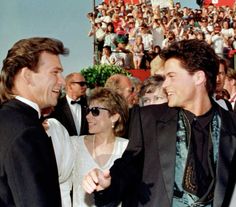 two men in suits standing next to each other at an event with people watching from the stands