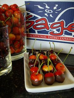 some cherries are sitting on a plate next to a glass of water and a sign