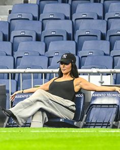 a woman sitting on the bleachers at a baseball game in black and grey