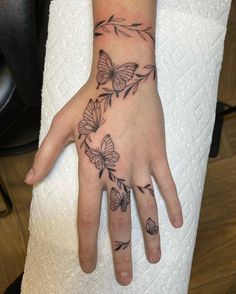 a woman's hand with butterflies on it and a flower tattoo on the wrist