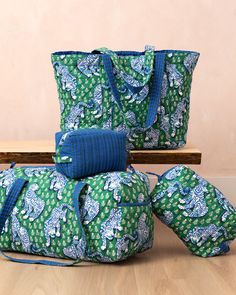 three green and blue bags sitting on top of a wooden table next to each other