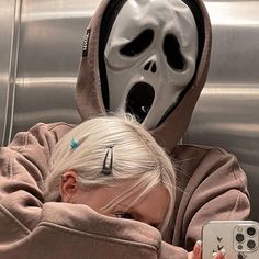 a woman taking a selfie with her cell phone in front of an alien mask