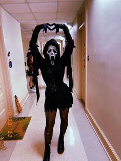 a woman dressed in black and white is walking down the hallway with her arms up