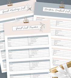 three wedding guest list cards with gold binders and white ribbon tied around the edges