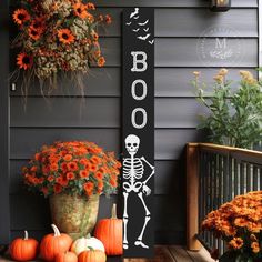 a halloween porch decoration with pumpkins and flowers in front of a sign that says boo