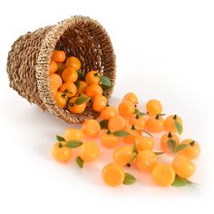 some oranges are in a basket and on the ground next to it is leaves