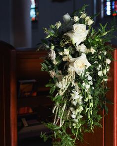 a bouquet of white flowers sitting on top of a wooden table in front of a pew