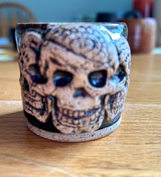 a ceramic skull mug sitting on top of a wooden table