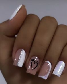 a woman's hand with white and pink nail polishes on her nails, holding a heart shaped manicure