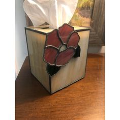 a tissue dispenser sitting on top of a wooden table next to a painting