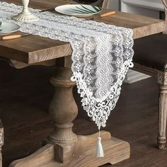 the table is set with two place settings and an ornate lace runner on top of it