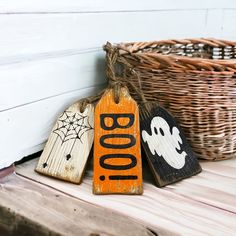 three wooden halloween tags sitting next to a wicker basket