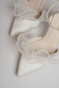 a pair of white wedding shoes with pearls on the toe and heels are sitting next to each other