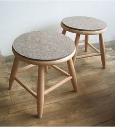 two stools sitting on top of a hard wood floor next to a white wall