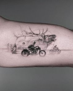 a man's arm with a deer and motorcycle tattoo on it