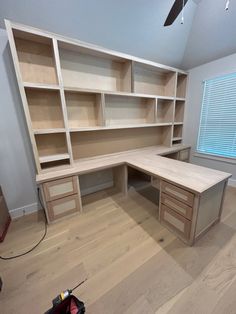 an empty room with some shelves and drawers on the wall next to a ceiling fan