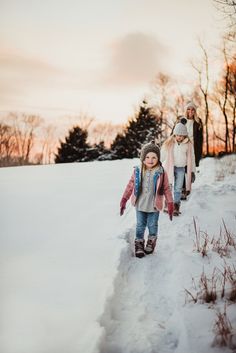 three children walking in the snow with their parents